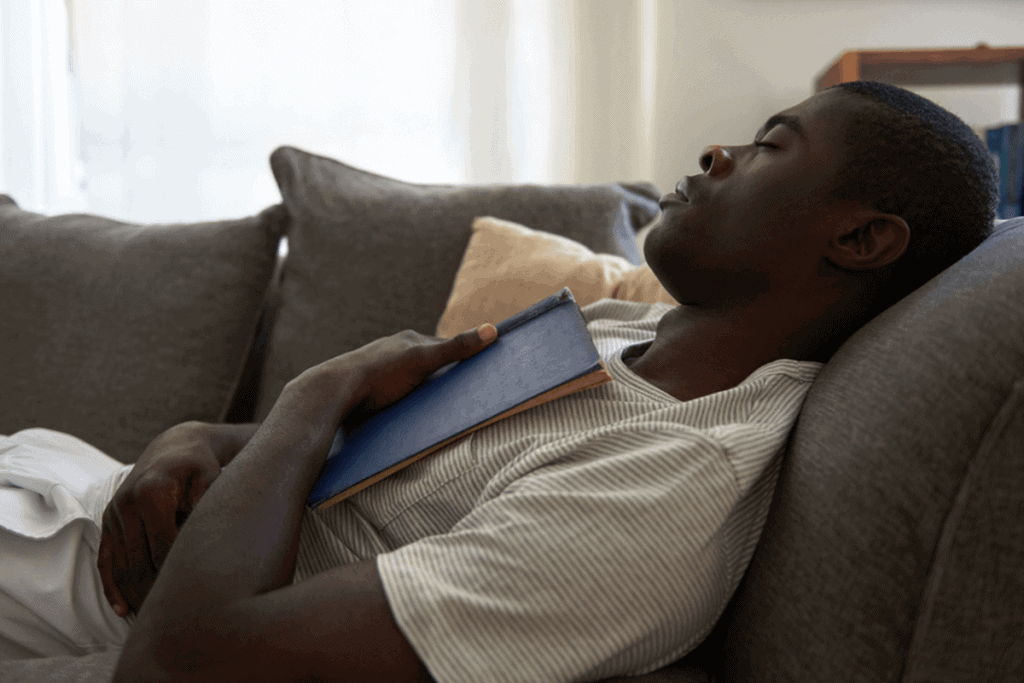 man sleeping on couch holding a book on his chest