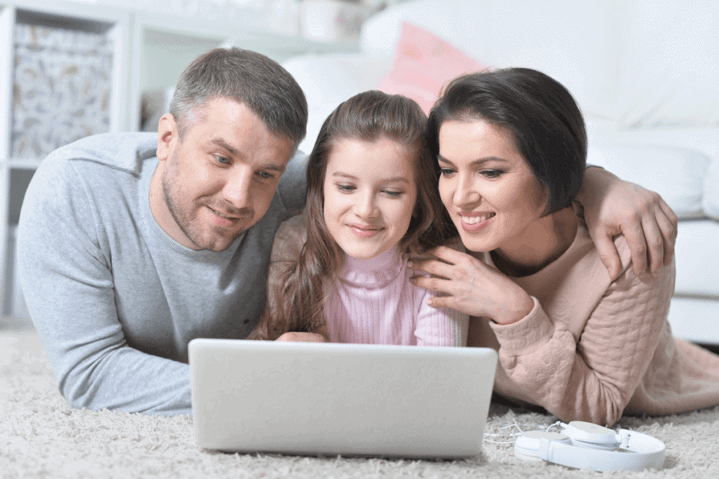 father, daughter, and mother watching something on laptop