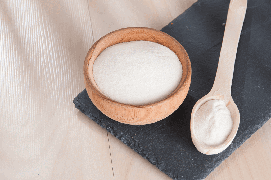 collagen protein in wooden bowl and on wooden spoon