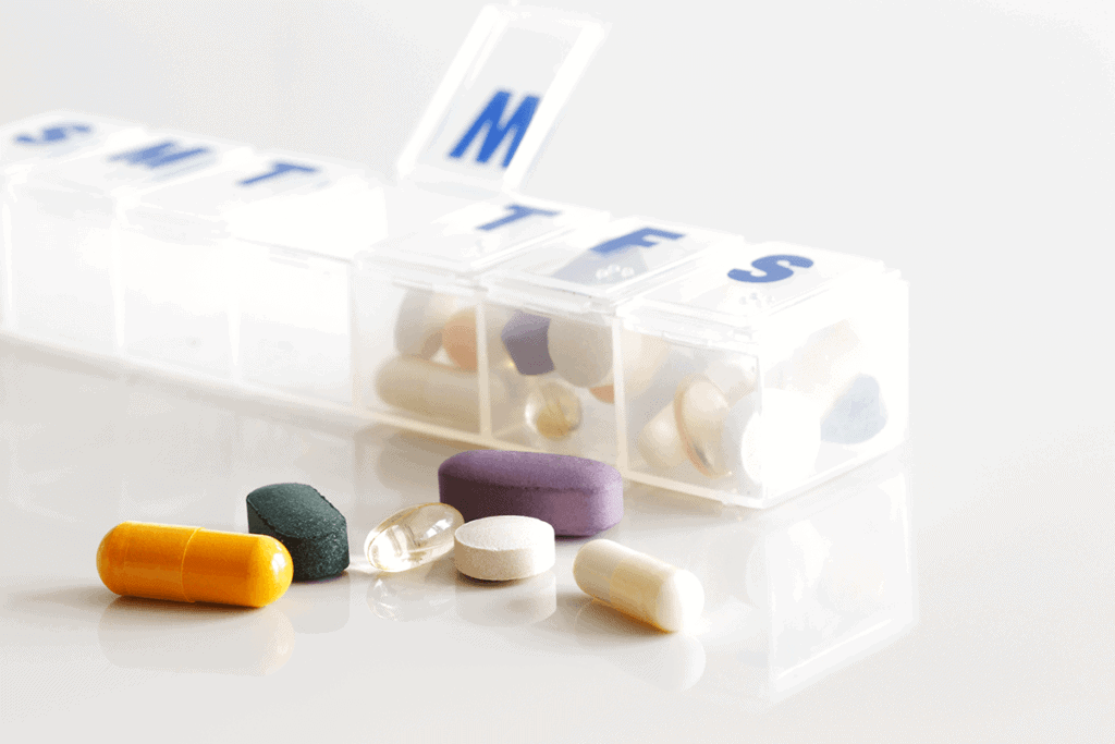 pill container with days of the week letters and capsules, softgels surrounding it