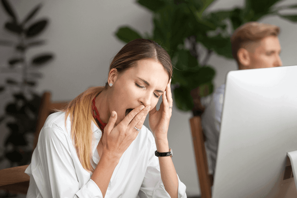 woman sitting at work desk and yawning