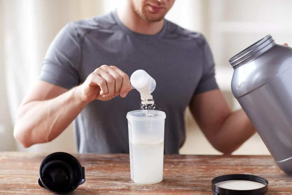 man putting protein powder into a water bottle