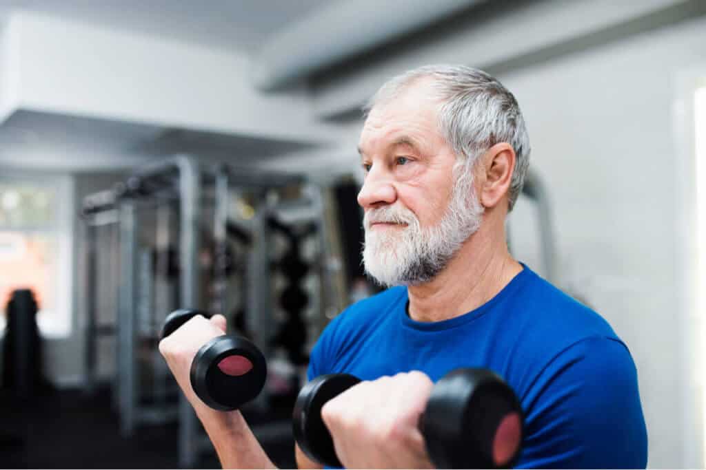 older man lifting dumbbells at the gym