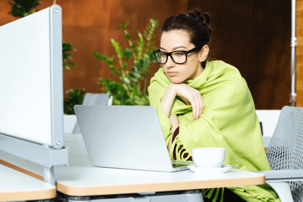 woman wrapped in a blanket looking at her laptop