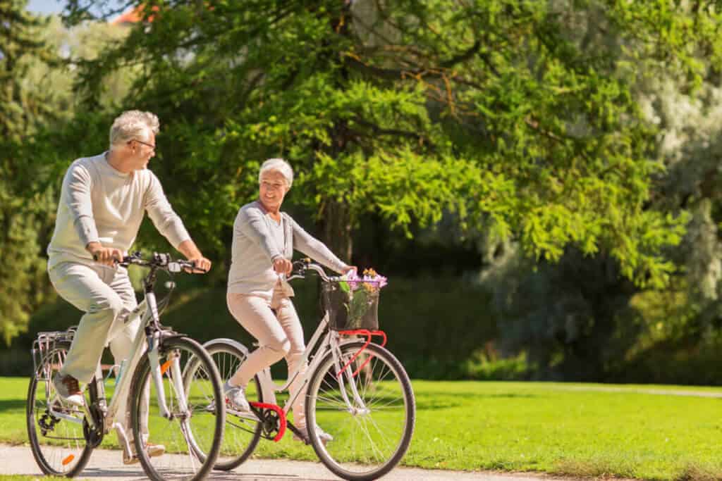 Older couple riding bicycles in a park.