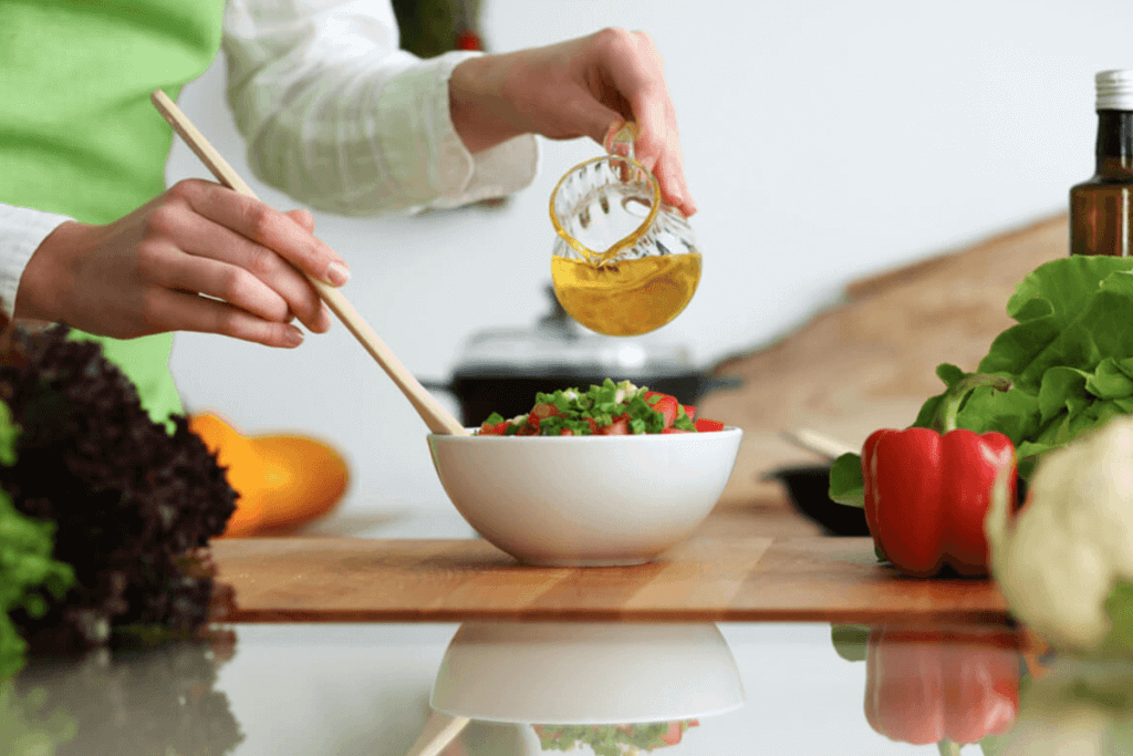 person pouring oil on a bowl of salad