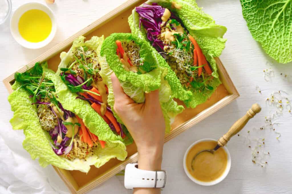 Colorful vegetarian lettuce leaf wraps on a white table.