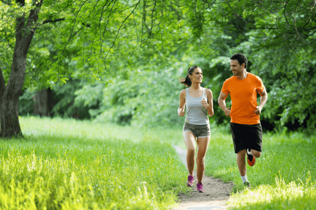Woman and man running through a park in the summer.