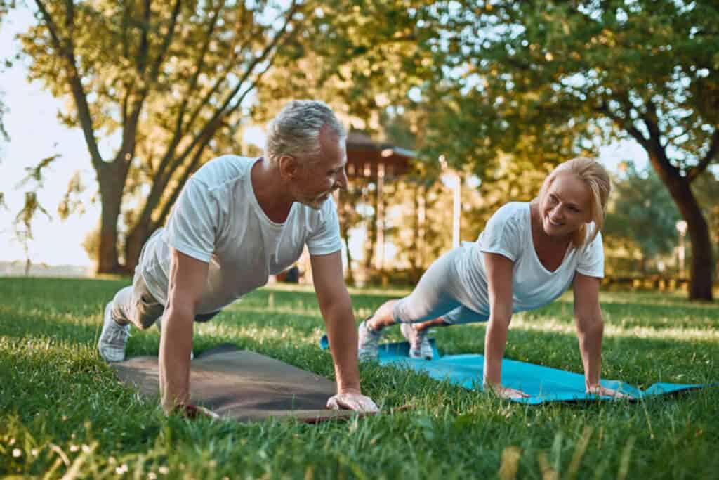 elder couple exercising outdoors on yoga matts