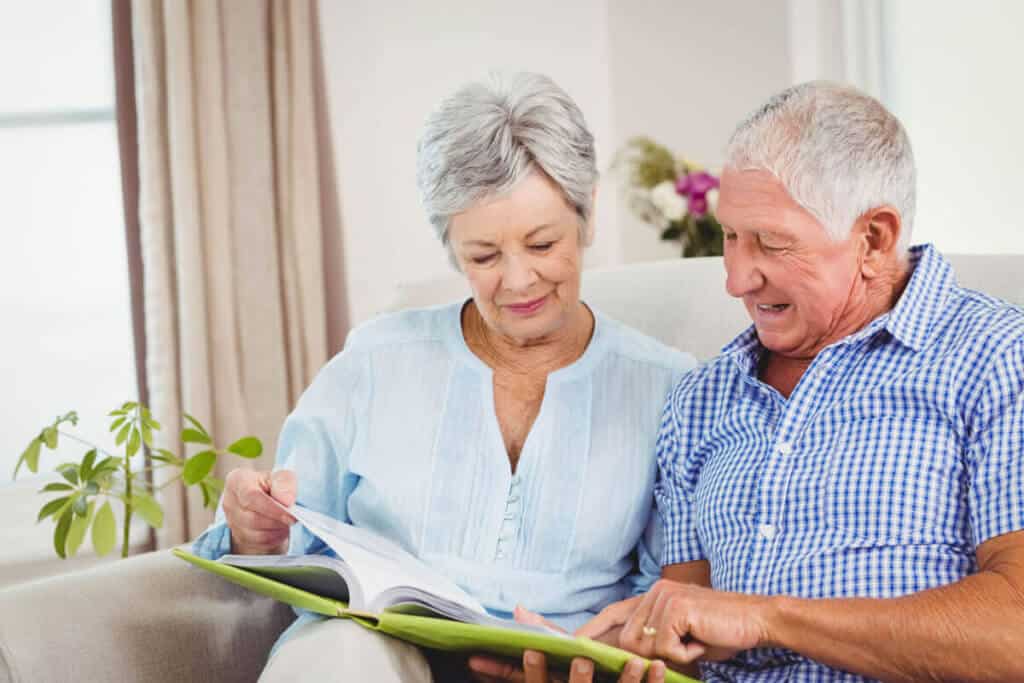older couple sitting on couch reading a book