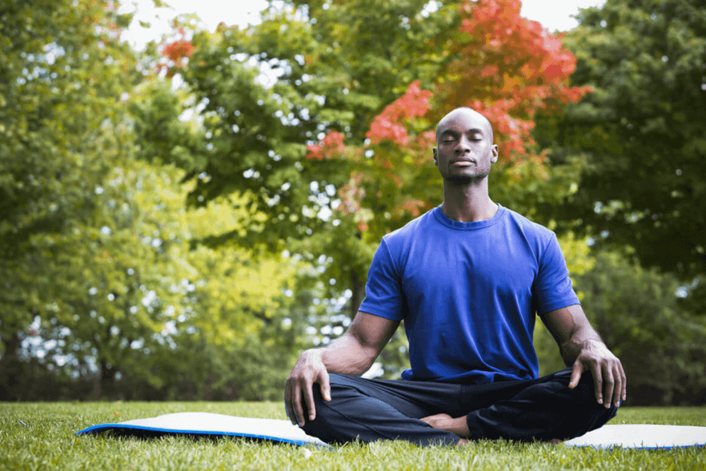 Man sitting cross-legged outdoors and meditating.