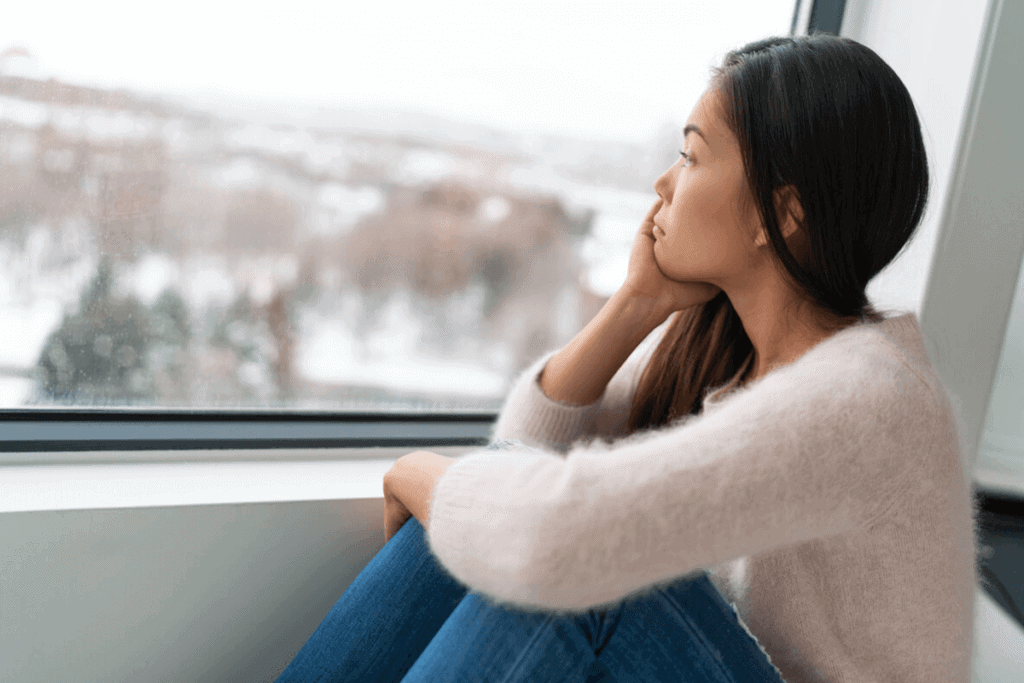 Young woman looking out of a window during winter.