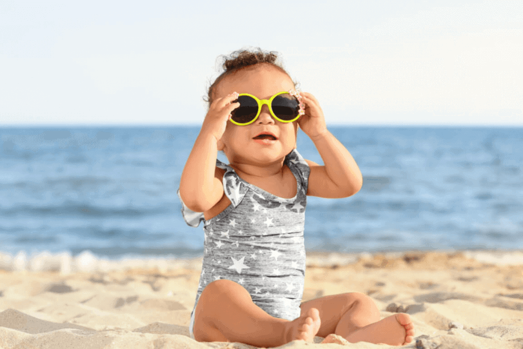 child sitting outdoors on a beach with sunglasses on