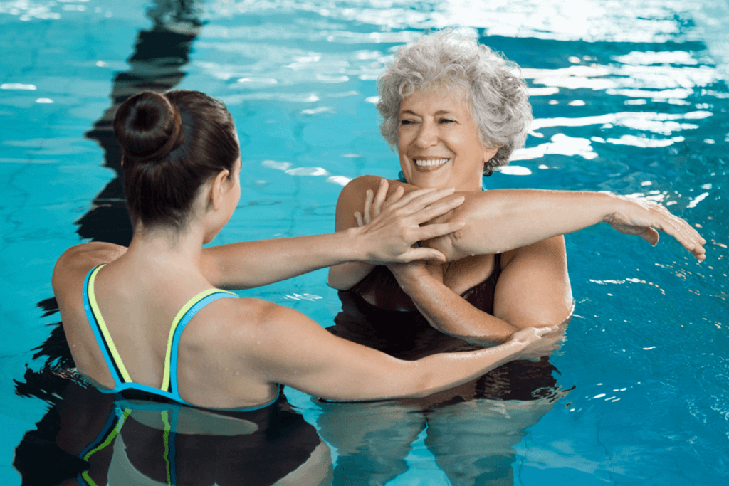 trainer with woman in the pool guiding in aquatic exercise