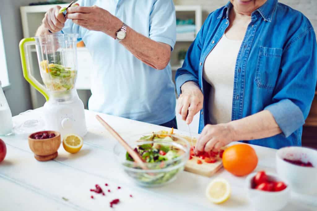 Elderly couple making healthy smoothie in kitchen