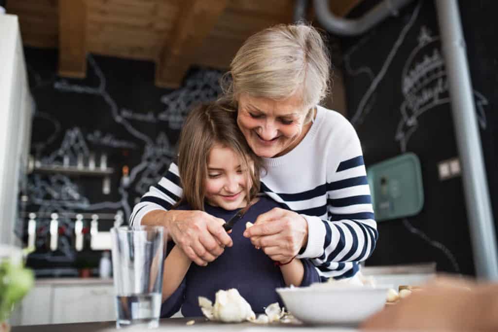 woman helping young girl peel garlic in kitchen