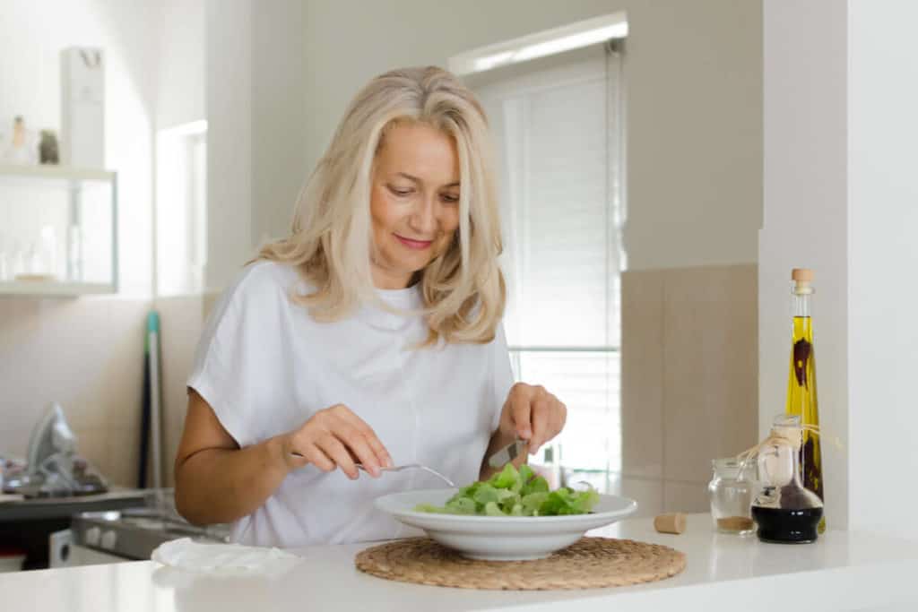 woman eating a salad in her kitchen