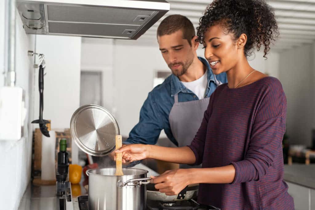 man and woman cooking in the kitchen, stirring a pot