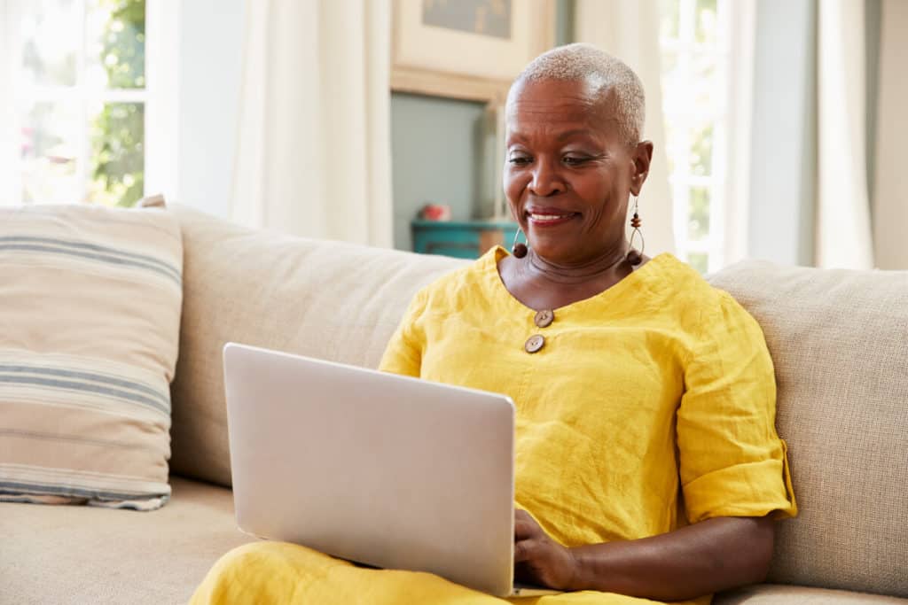 woman typing on her laptop sitting on her couch