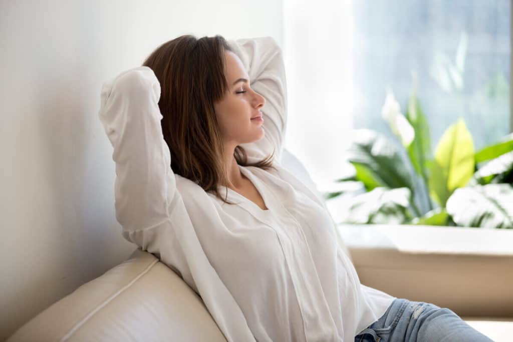 Woman sitting on sofa with her eyes closed
