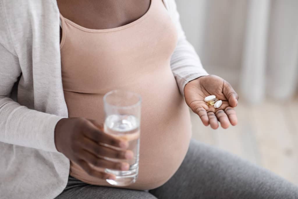 Pregnant woman holding vitamins and a glass of milk