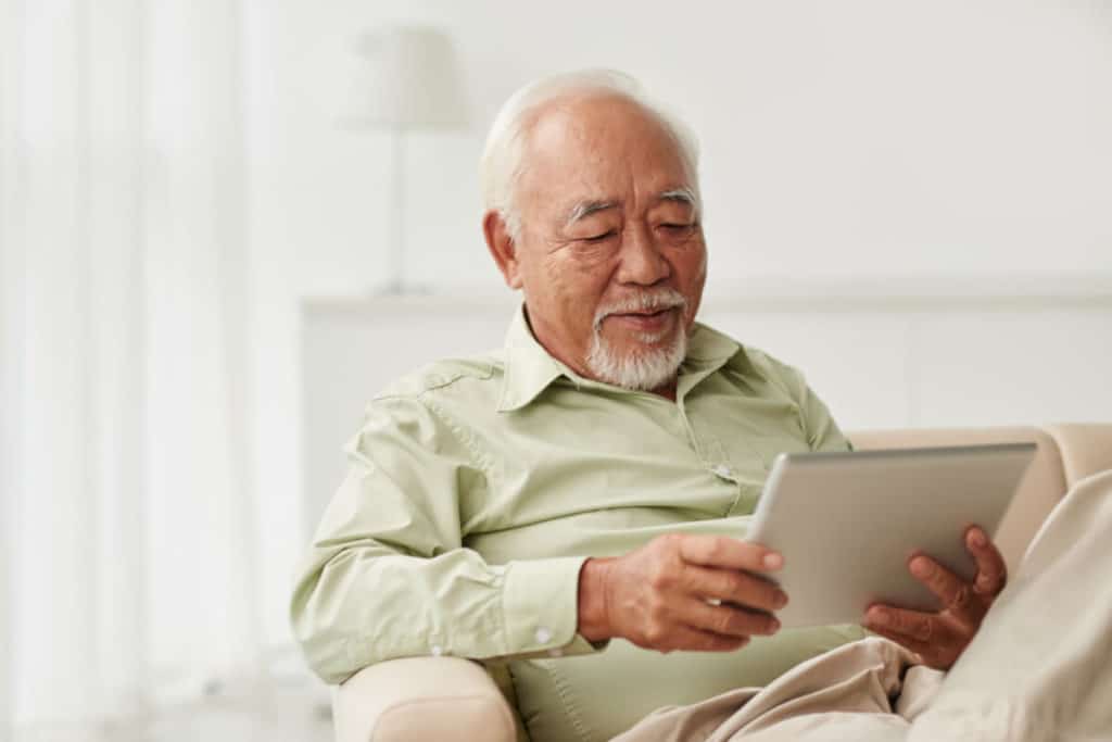 Elderly man reading on a tablet