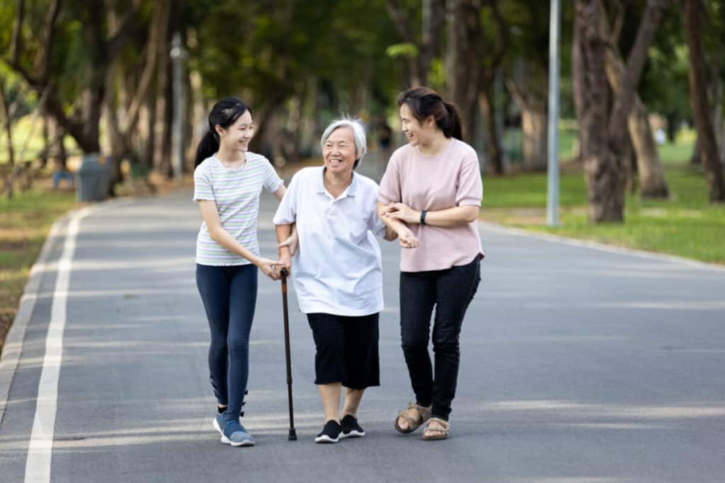 Two woman helping elderly woman down the street