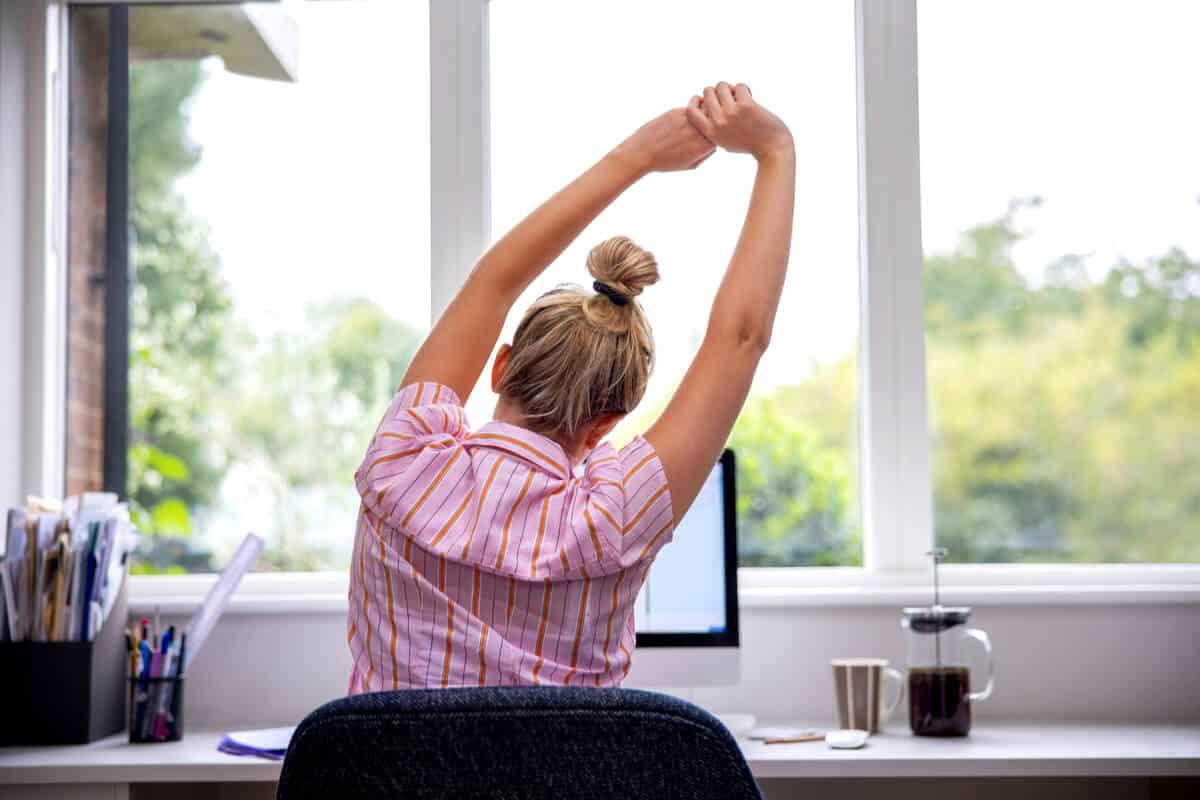 Woman siting at a desk stretching
