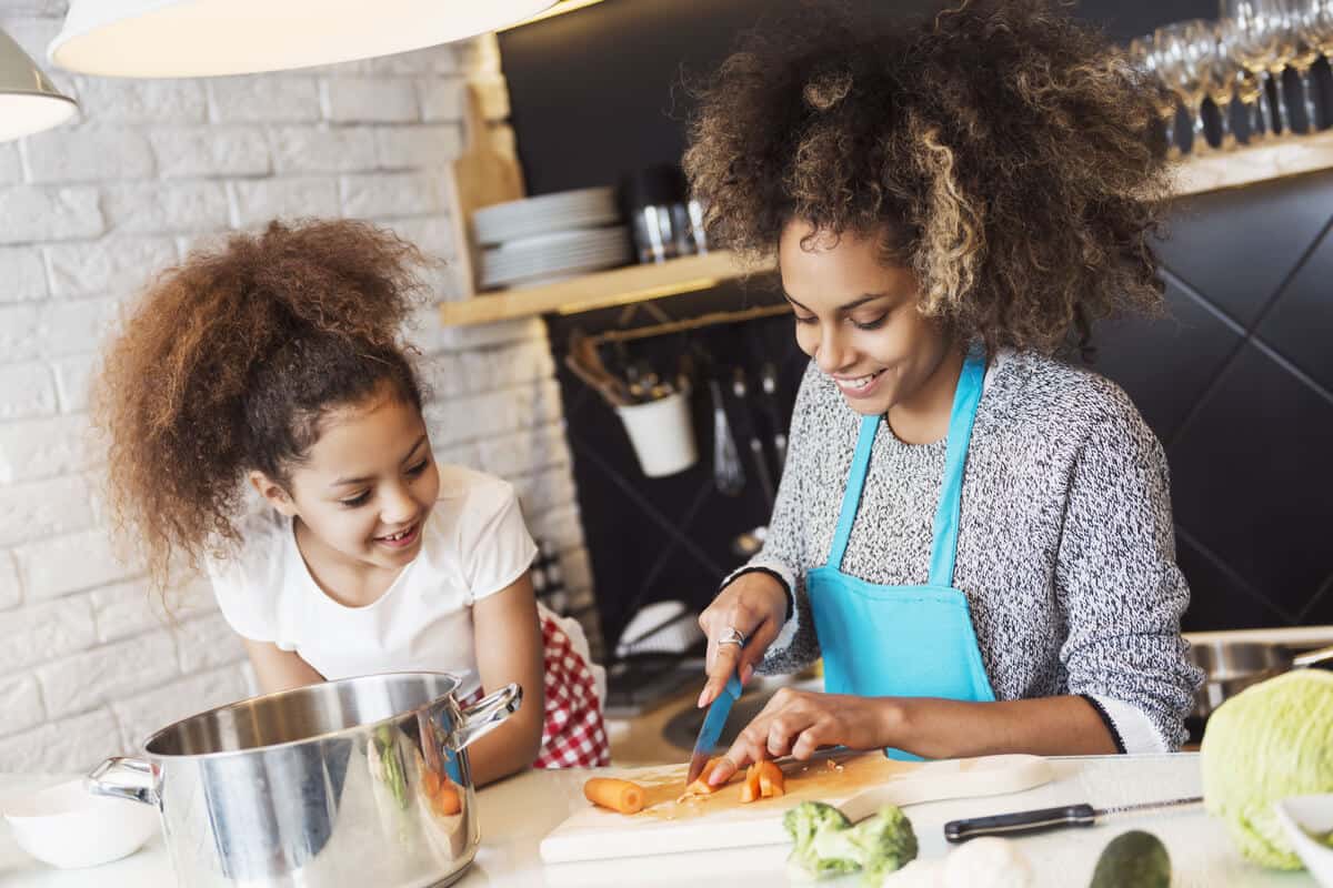 mom cutting up vegetables with young daughter