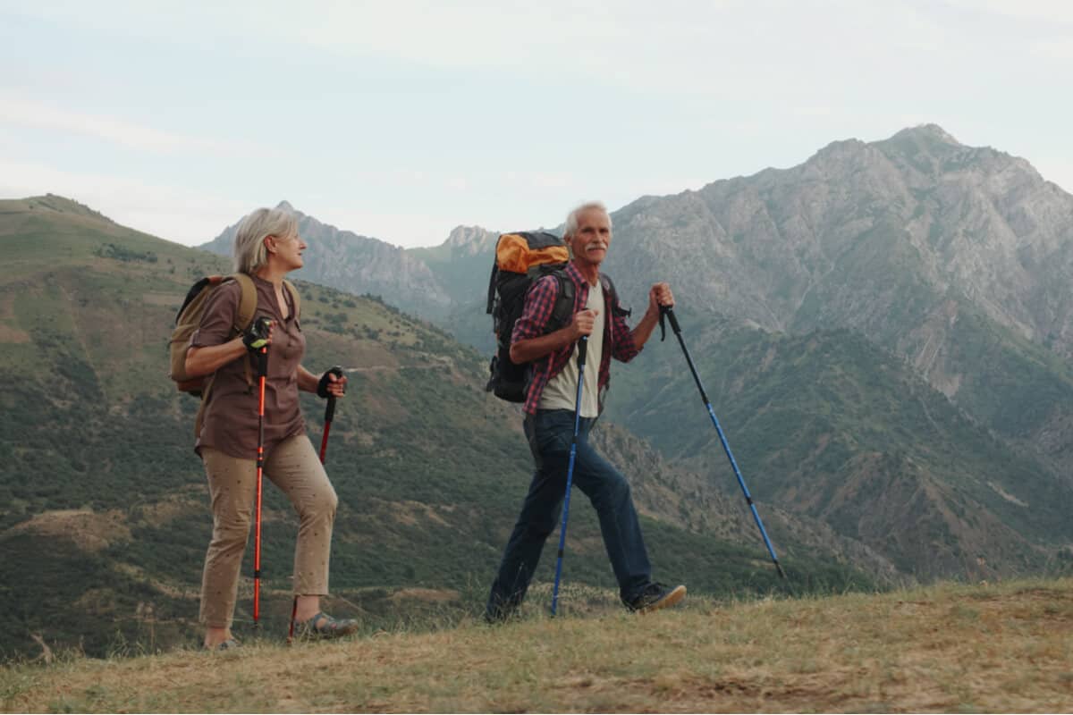 two people hiking with backpacks and hiking sticks