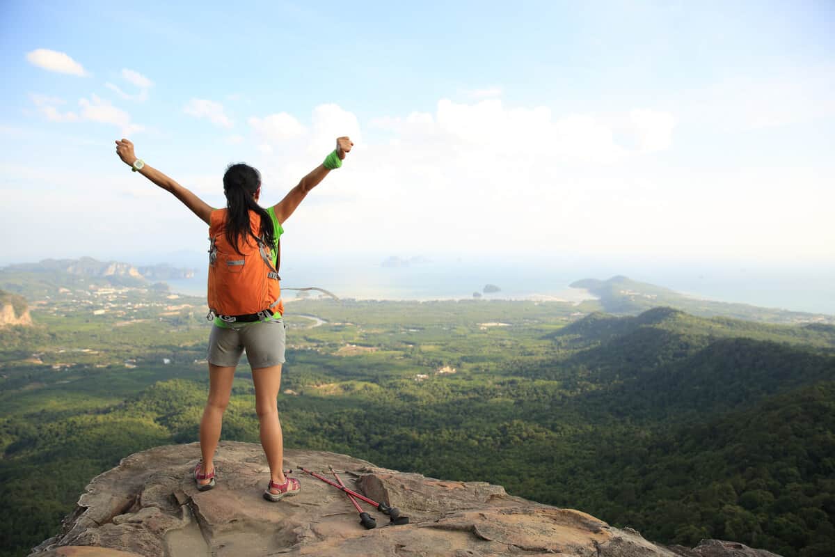woman on top of a mountain with her arms up stretching