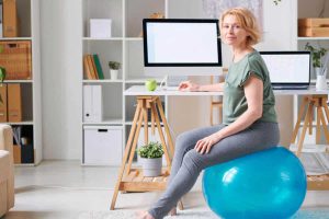 woman sitting on a gym ball at her desk set up at home