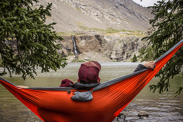 man laying in a hammock looking into the mountains outdoors