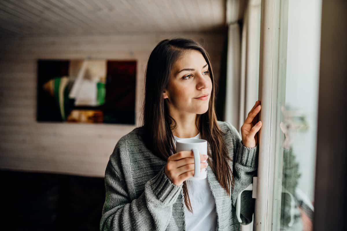 Woman holding a mug looking out a window