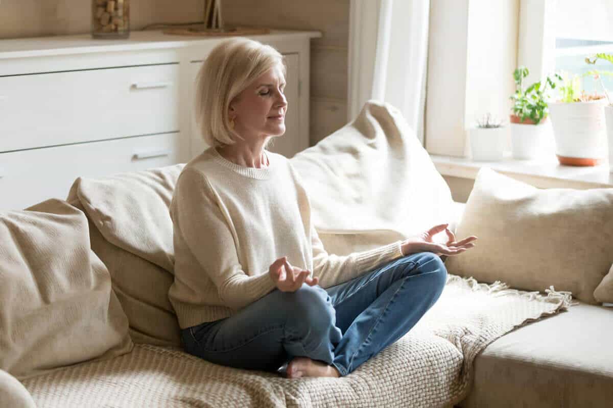 woman meditating on her couch in living room