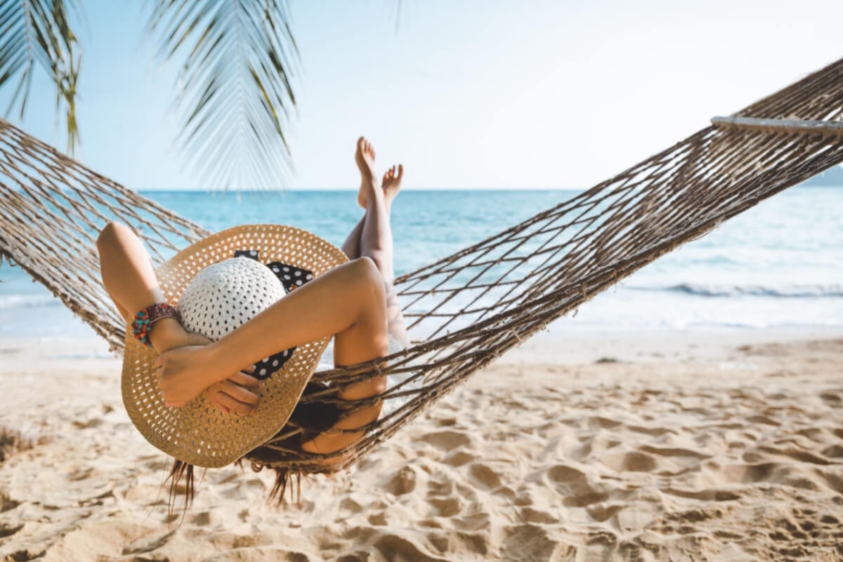 skin self exam woman laying in a hammock on a beach